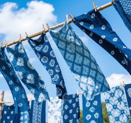 Traditional indigo tie-dye shibori textiles air drying on outdoor bamboo clotheslines against blue sky