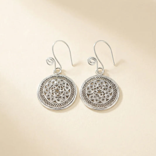 Pair of Miao silver earrings with intricate designs on a beige background