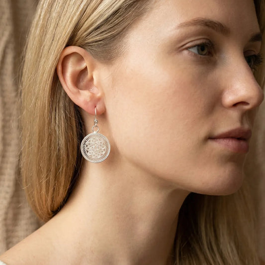 Close-up of a woman wearing a miao silver earring with a intricate design.