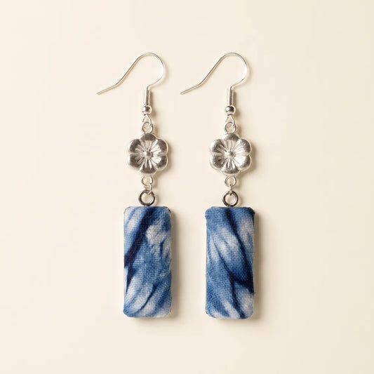 Pair of miao batik earrings with blue marbled design on a beige background