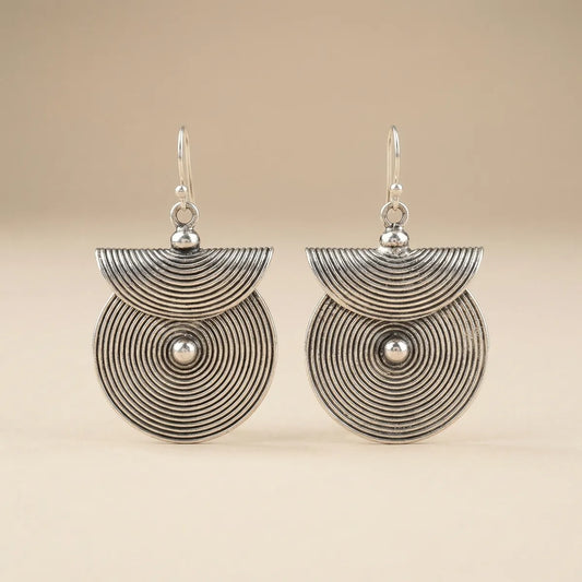 Pair of miao silver earrings with circular designs on a beige background