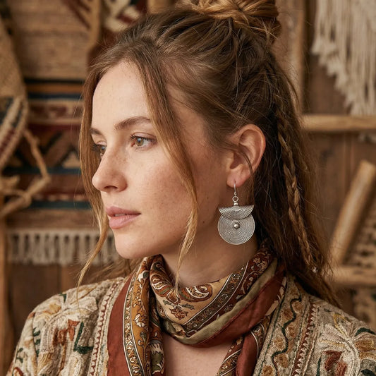 Woman wearing a patterned scarf and miao silver earrings in a warm-toned interior setting