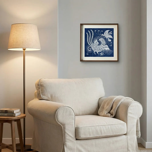 Beige armchair in a living room with a lamp and framed Miao batik artwork on the wall.