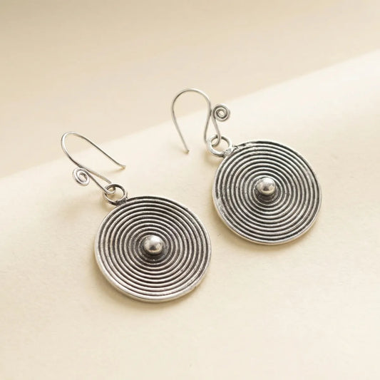 Pair of Miao silver spiral earrings on a beige background