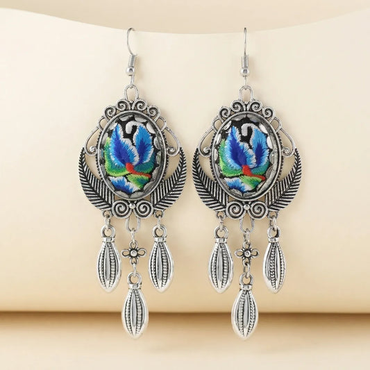Pair of earrings with colorful leaf design on a beige background
