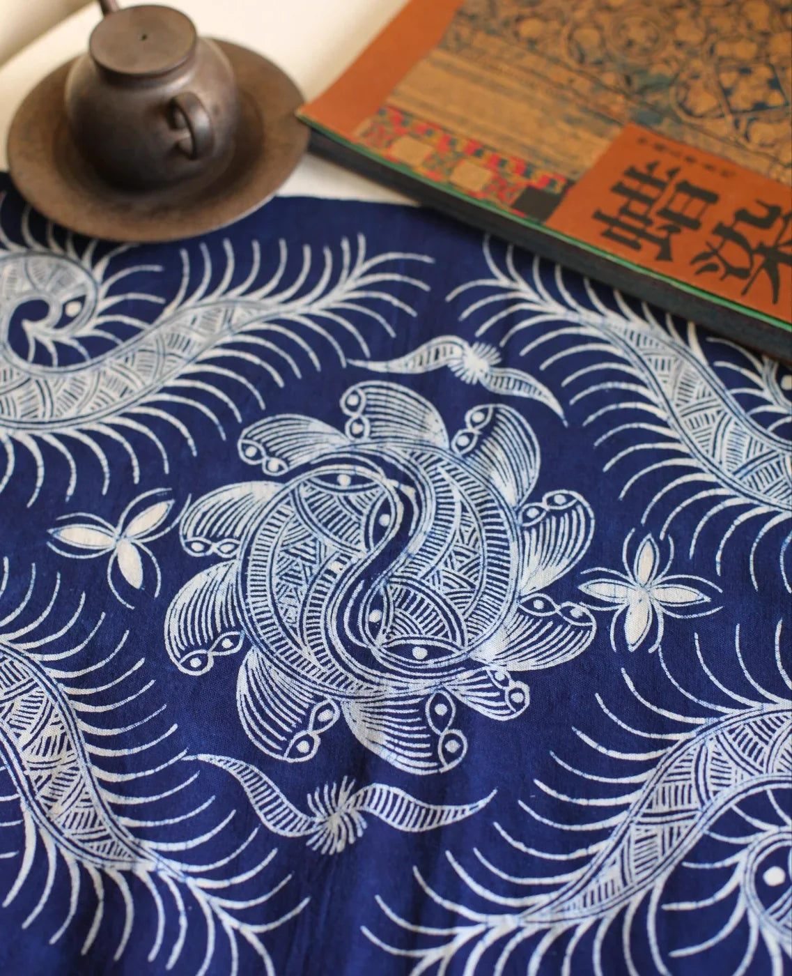 Miao batik fish motif textile styled with tea objects on a table