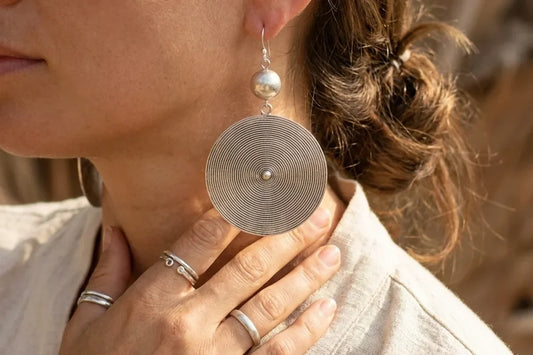 Silver-tone boho statement disc earrings worn with a neutral linen top