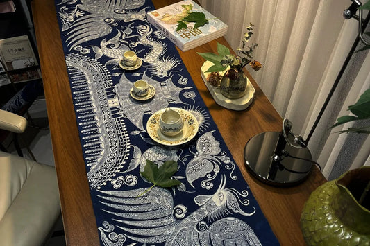 Indigo Miao batik table runner styled across a wooden dining table with tea cups, books and flowers