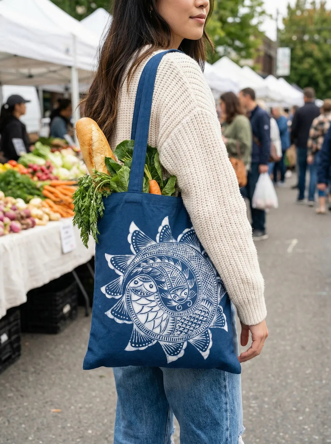 Person carrying a Miaozu Batik tote bag with a sun design at an outdoor market.