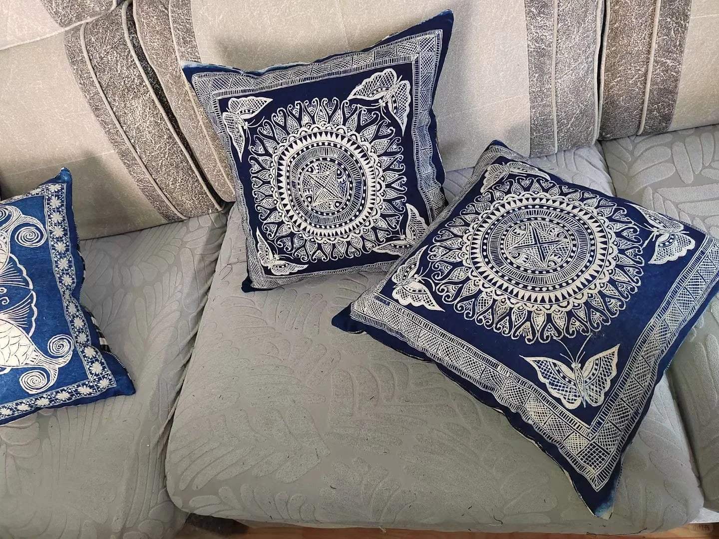 Coussins en batik Miao bleu et blanc disposés sur un canapé clair