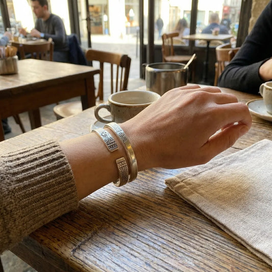 Person's hand with Miao silver bracelets on a table in a cafe setting