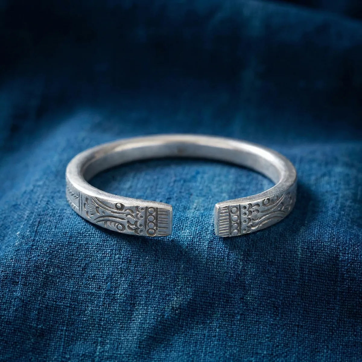 Miao Silver bracelet with intricate designs on a blue fabric background