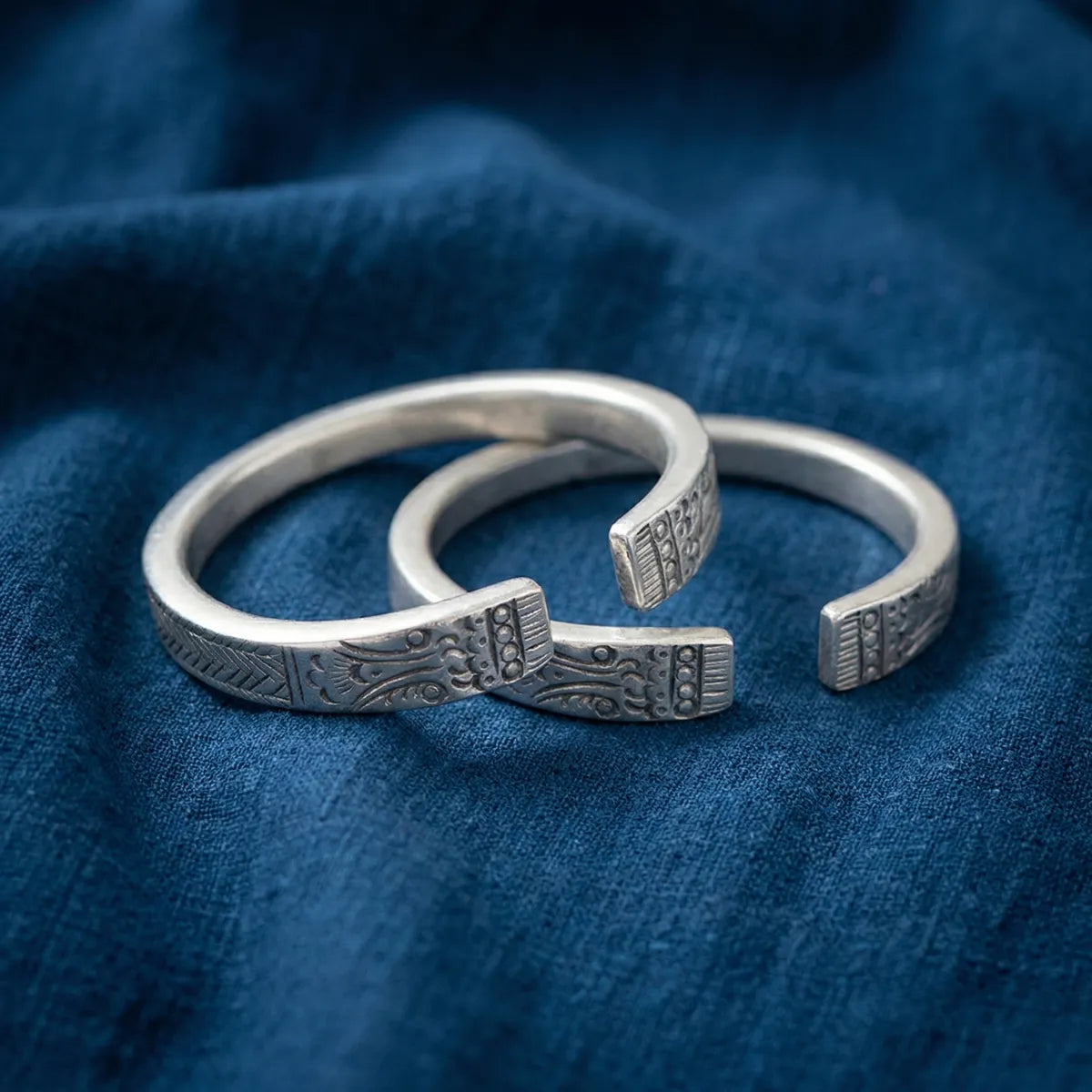 Two miao silver bracelets on a blue fabric background
