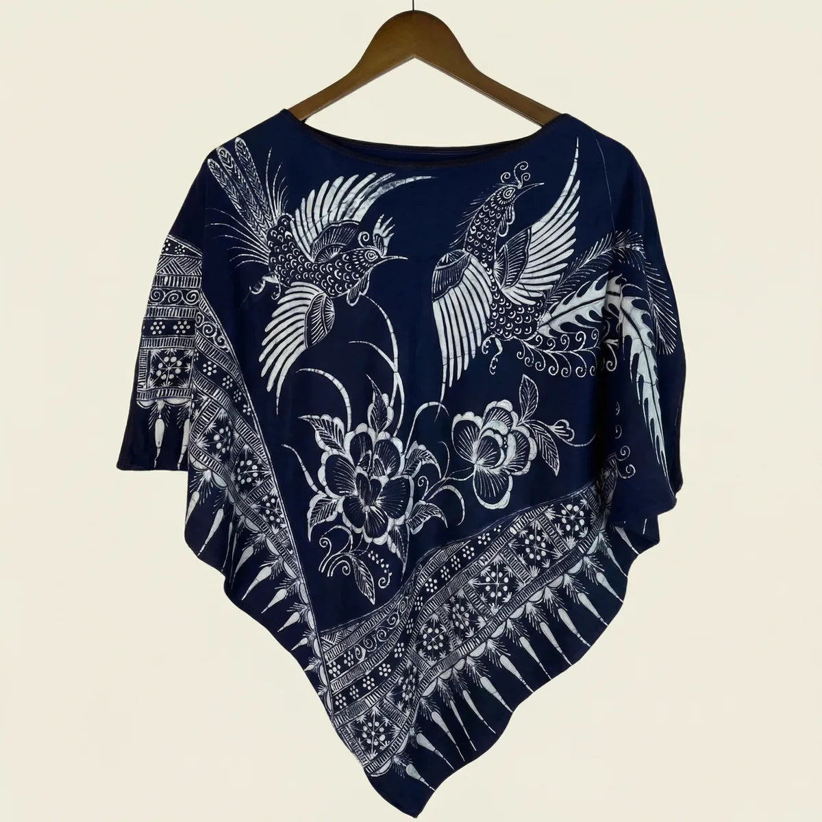 Miao batik poncho with white floral and bird patterns on a beige background