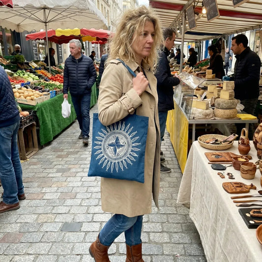 Woman walking through a market with a miao batik tote bag featuring a sun design.