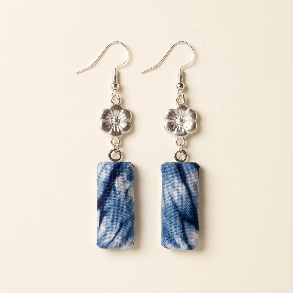 Pair of miao batik earrings with blue marbled design on a beige background