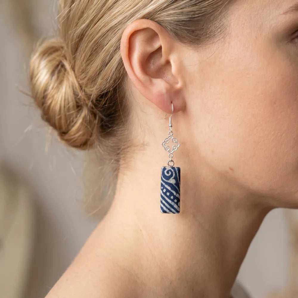 Close-up of a woman wearing a blue and white patterned miao batik earring.