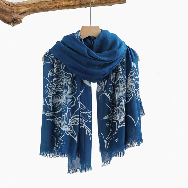 Blue Miao batik scarf with white floral patterns on a wooden hanger against a white background