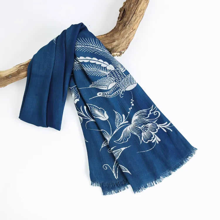 Blue Miao batik scarf with white floral patterns draped over a branch on a white background
