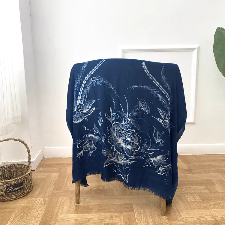Navy blue Miao batik scarf draped over a chair in a room with a white wall and wooden floor.
