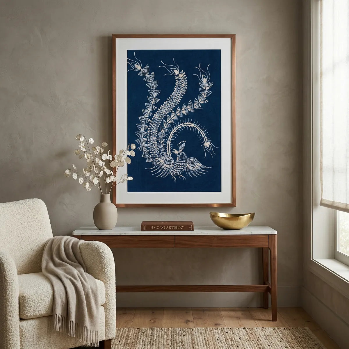 Framed Miao Batik artwork of a phoenix design on a wall above a wooden table with decorative items.