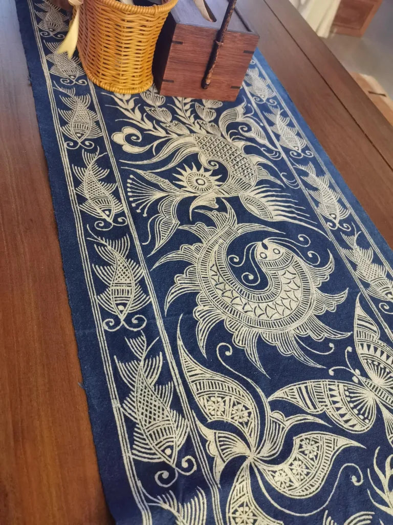 Decorative miao batik table runner with intricate white patterns on a blue background