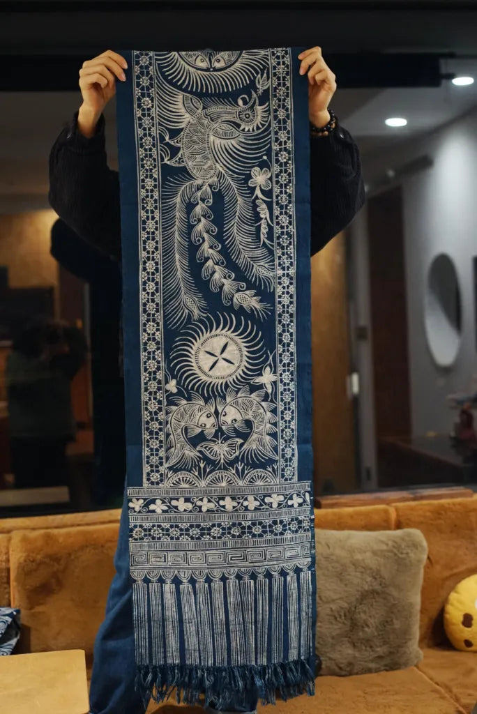 Person holding a blue and white patterned miao batik tapestry with fringe details.