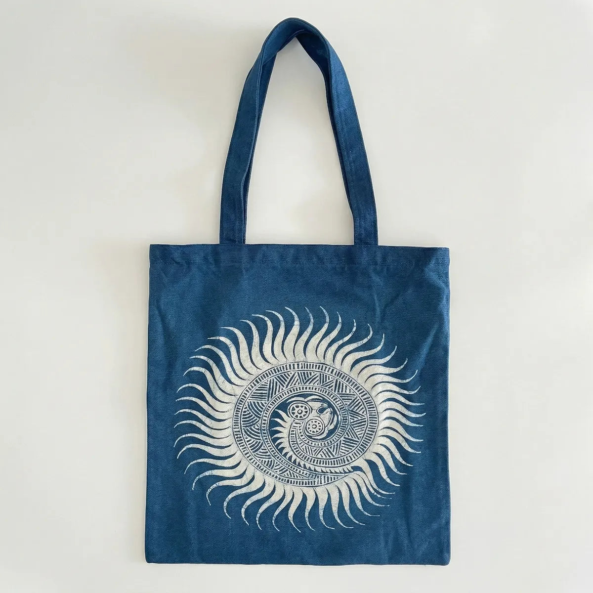 Miao batik tote bag with white sun design on a light gray background