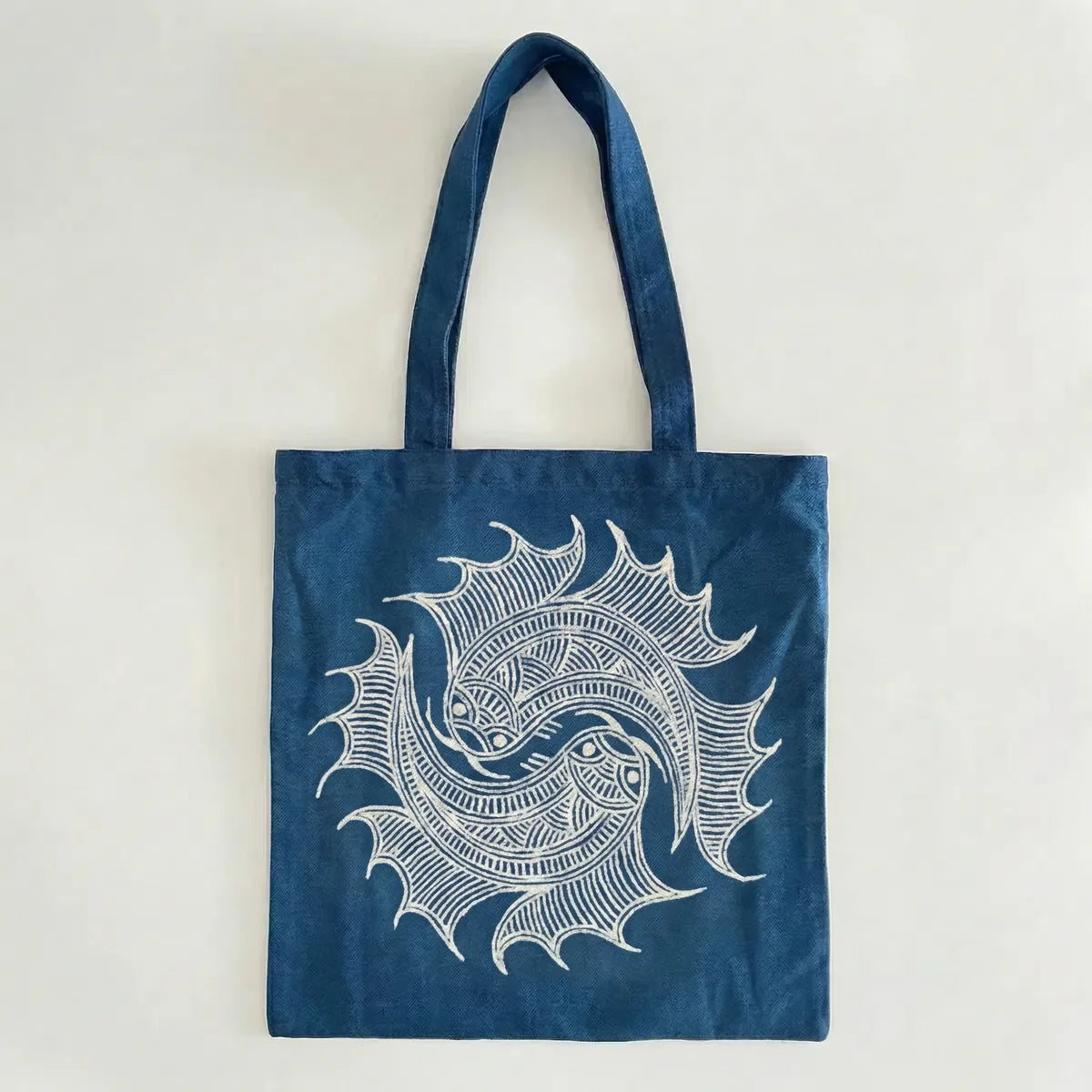 Miao batik tote bag with white decorative design on a light gray background