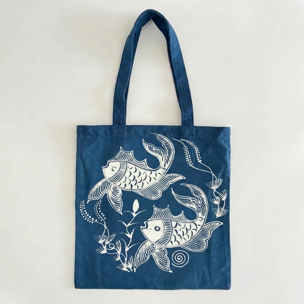 Miao batik  tote bag with white fish design on a light gray background