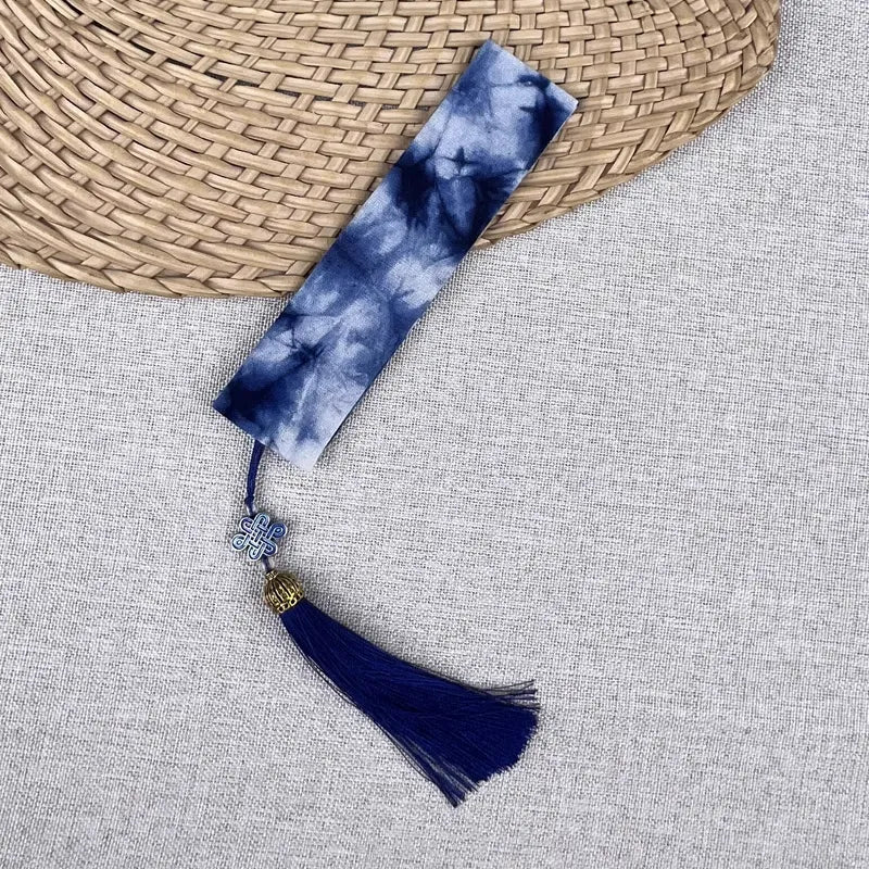 Blue tie-dye bookmark with a tassel on a textured surface