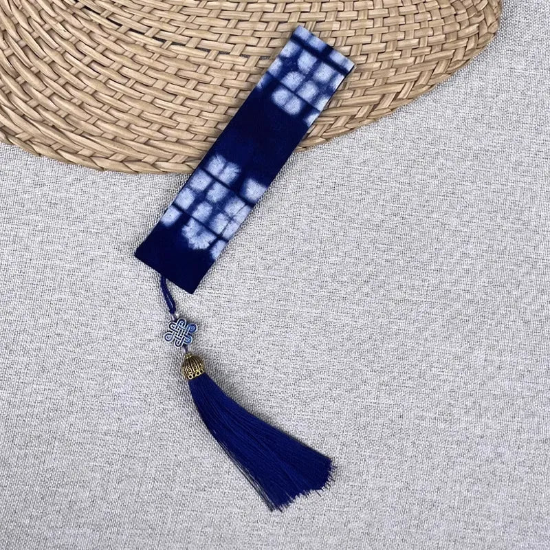 Blue and white tie-dye bookmark with tassel on a textured surface