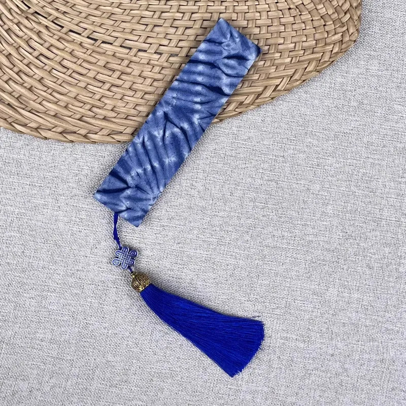 Blue velvet miao batik bookmark with tassel on a textured surface