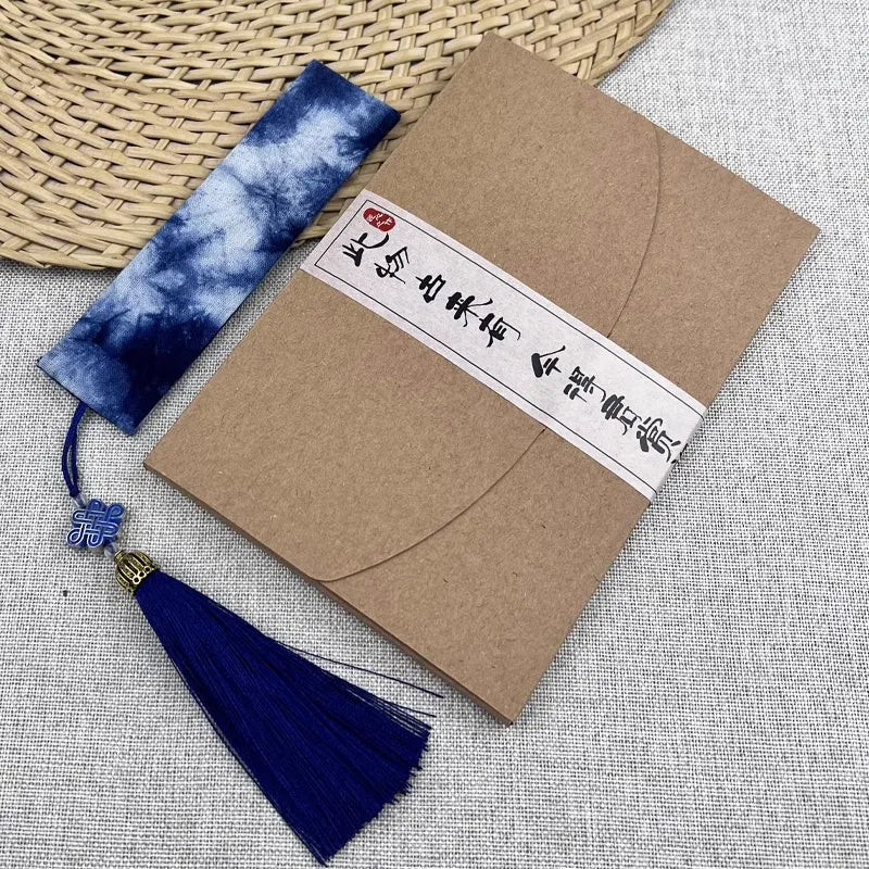 Kraft paper envelope with blue tassel and decorative label on a textured surface