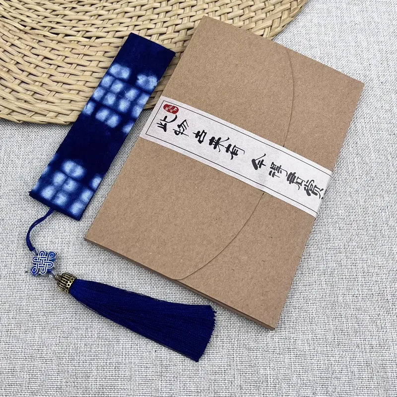 Kraft paper envelope with a decorative blue tassel batik bookmark on a textured surface
