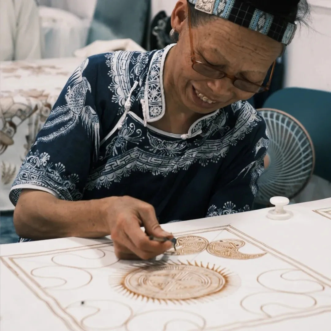 A Miao artisan drawing wax patterns by hand on fabric