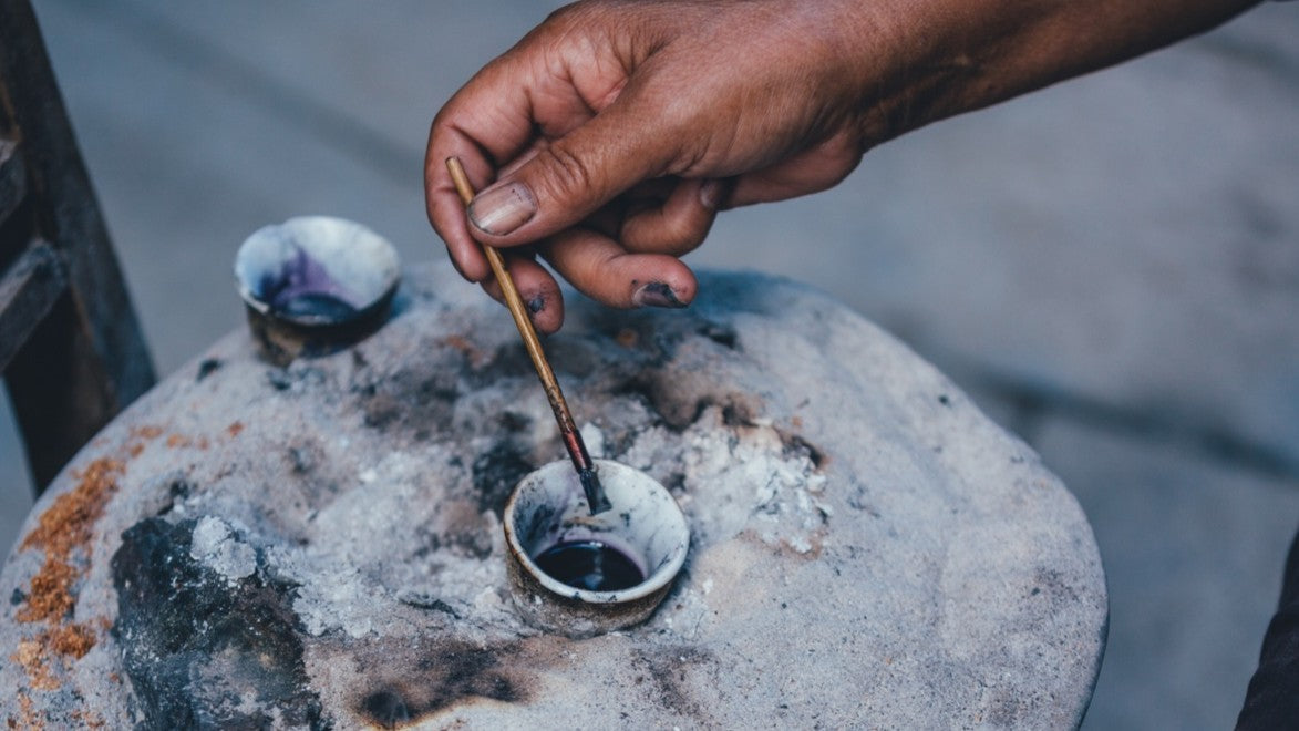 Tremper un couteau à cire de batik dans de la cire fondue à la bonne température