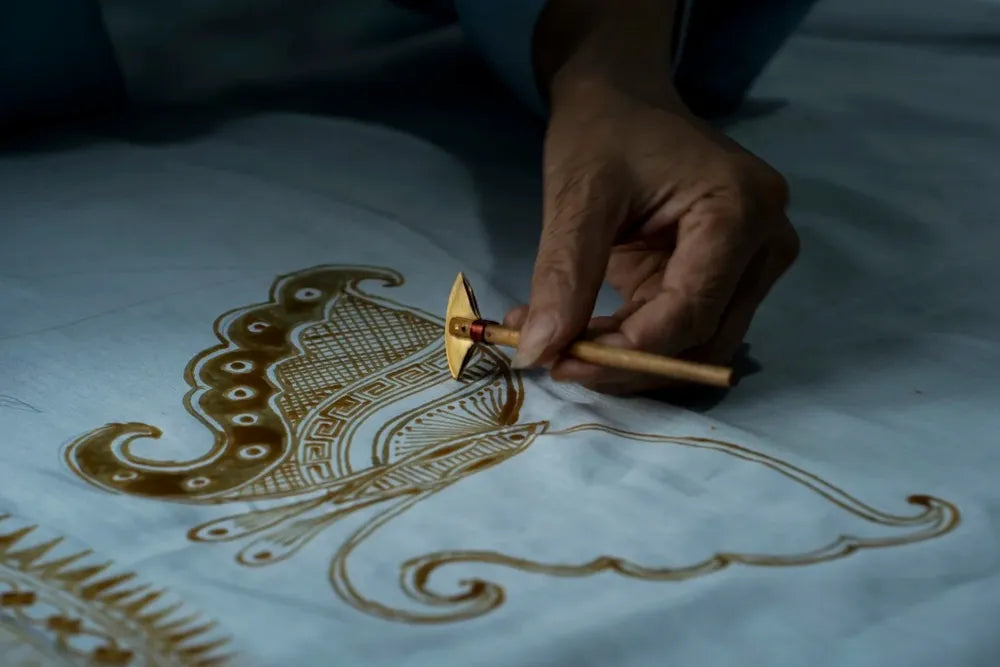 Heißes Wachs mit einem Batik-Wachsmesser auf gespannten Stoff zeichnen