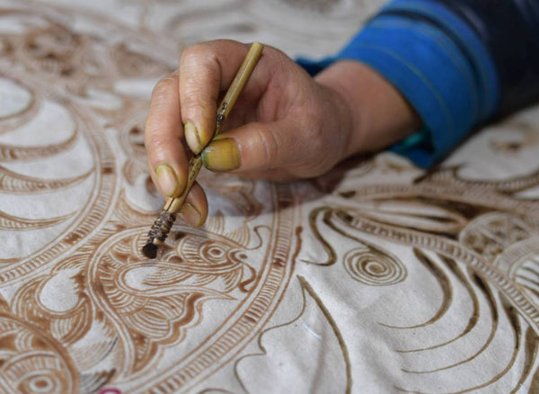 Artisan drawing wax lines on cloth with a Miao batik tool