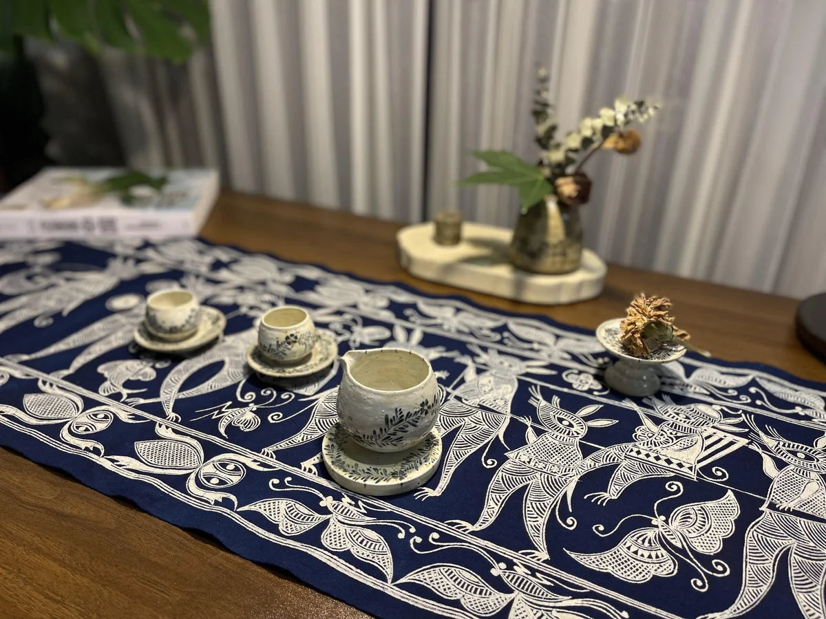Authentic hand-dyed indigo batik table runner displayed on a solid wood tea table