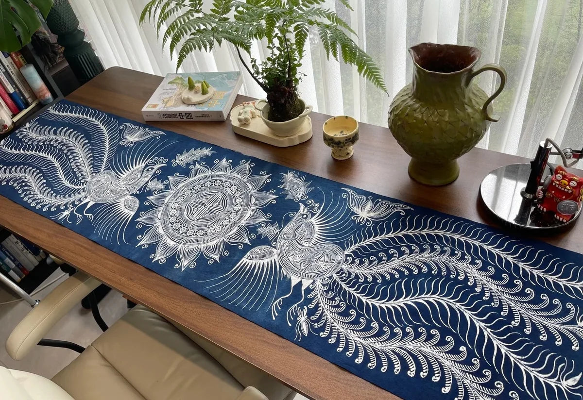 Chemin de table en batik indigo sur une table en bois avec des plantes et des objets décoratifs