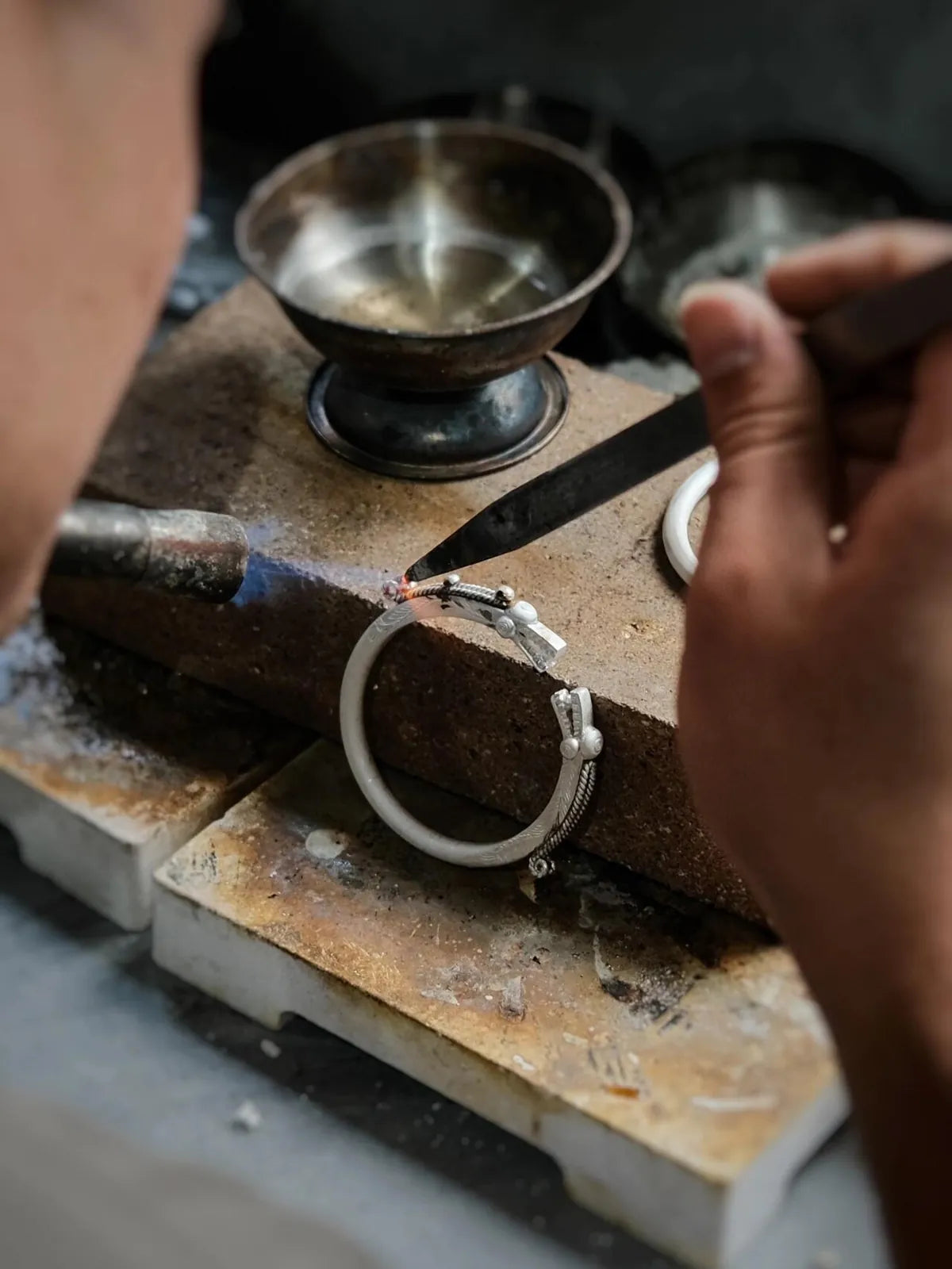 Master silversmith assembling delicate filigree wires using tweezers in a Guizhou workshop