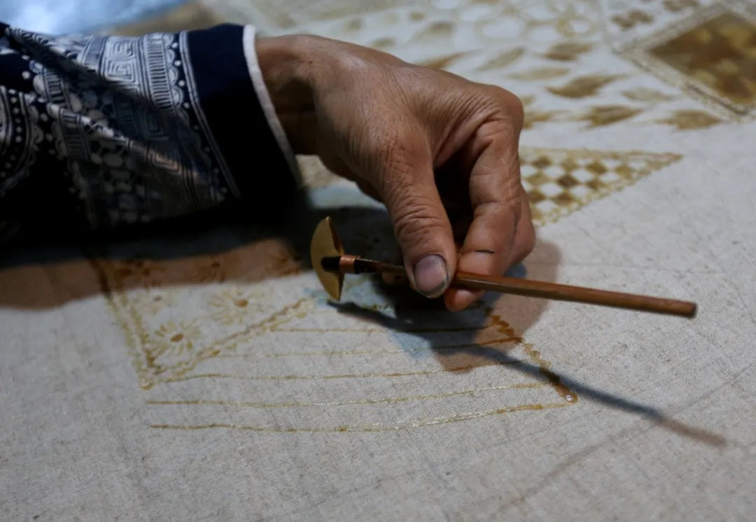 Close-up of hand using wax knife for batik drawing