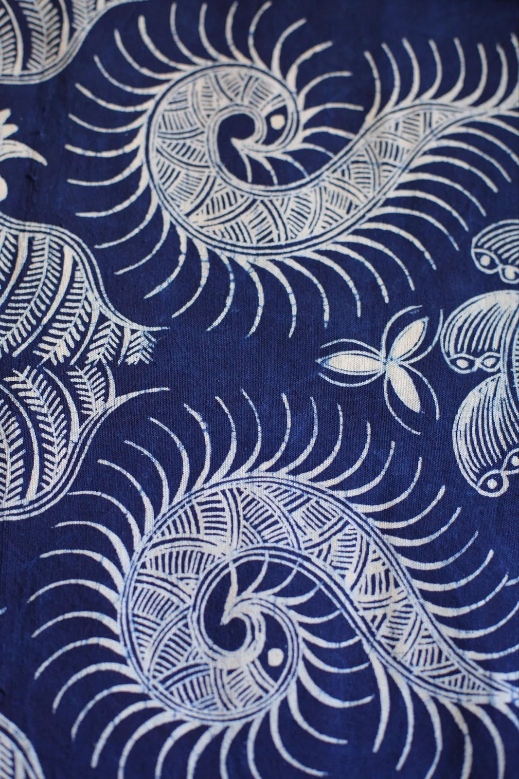 Close-up of Miao batik spiral fish motifs drawn in white on indigo cloth