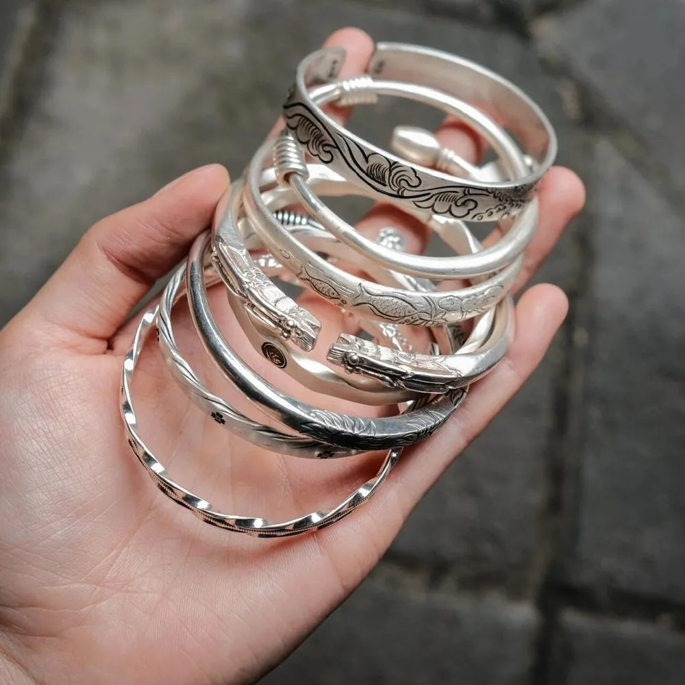 Hand holding traditional Miao silver bracelets