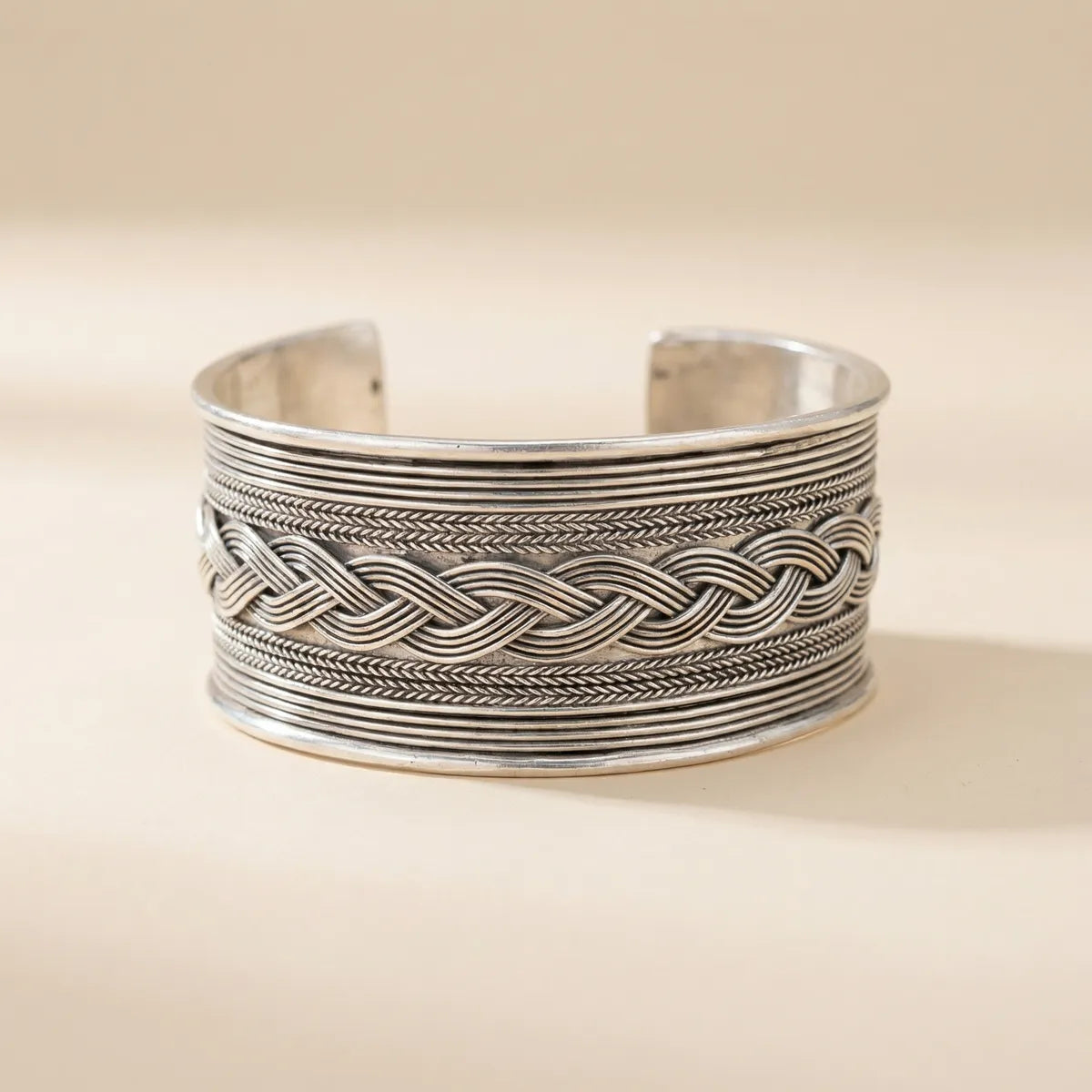 Miao Silver braid patterned cuff bracelet on a beige background