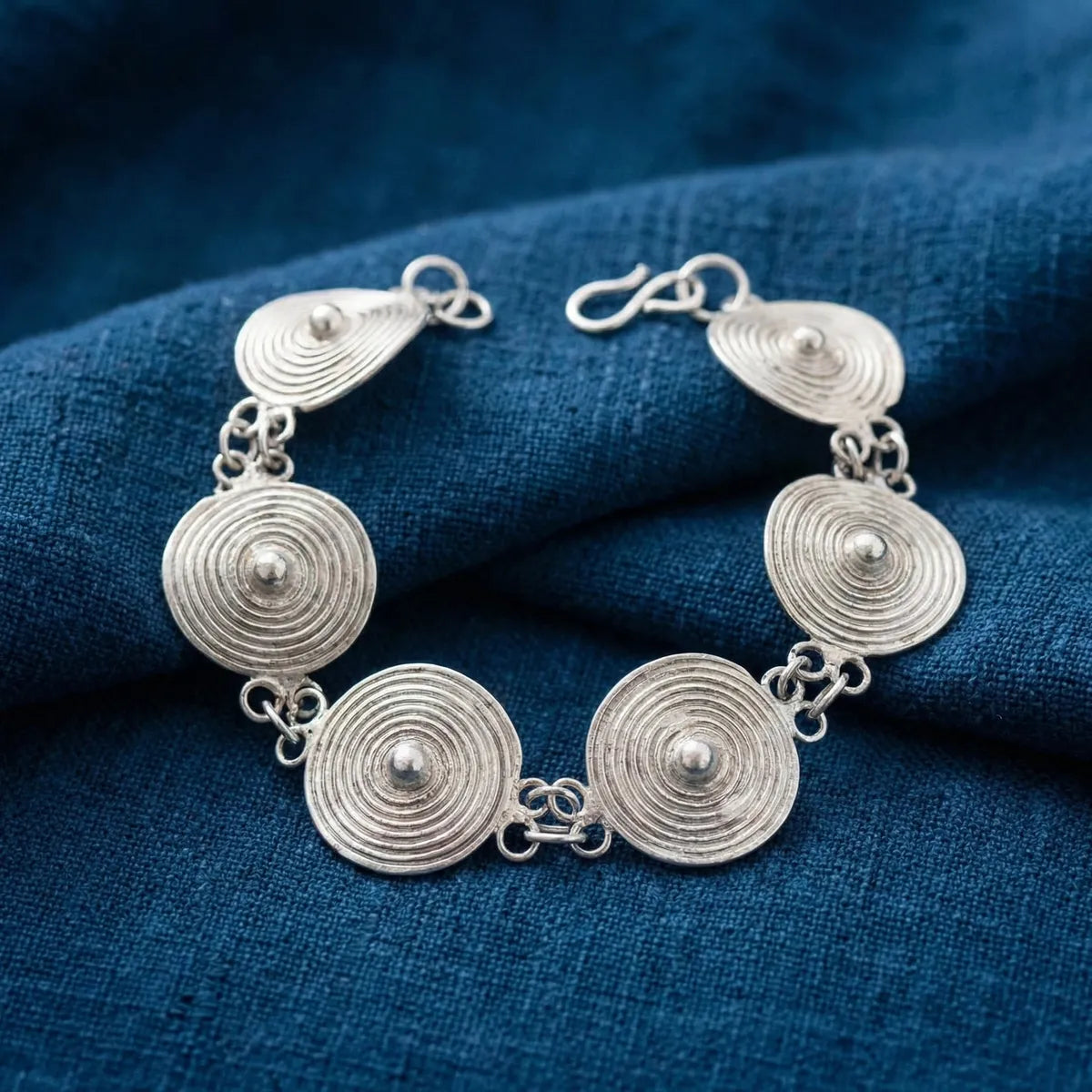 Miao Silver bracelet with circular designs on a blue fabric background