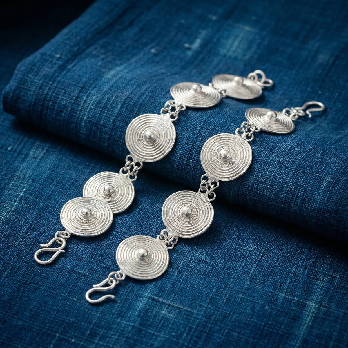 Miao Silver bracelet with circular designs on a blue fabric background