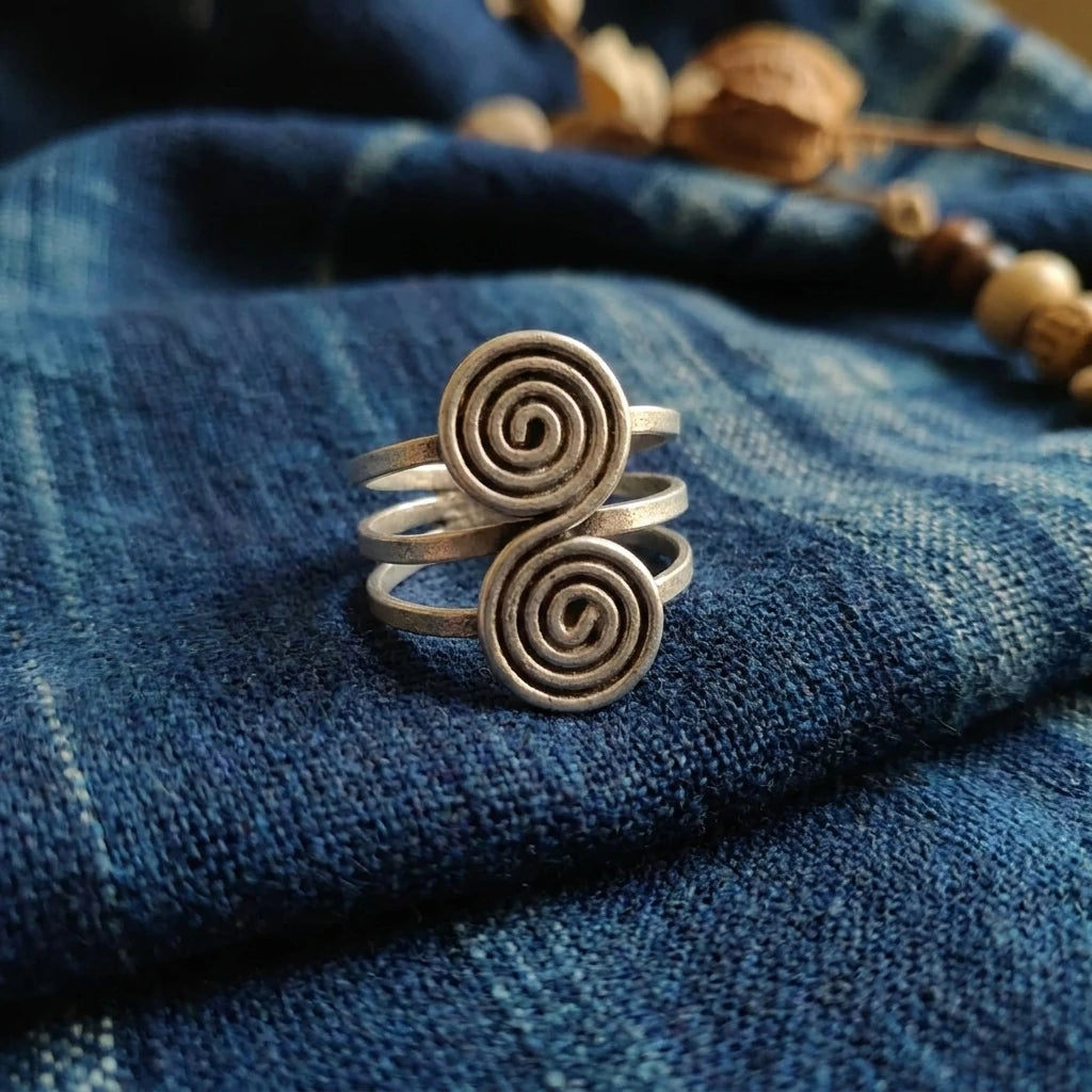 Miao Silver Double Disc Spiral Ring displayed on indigo textile