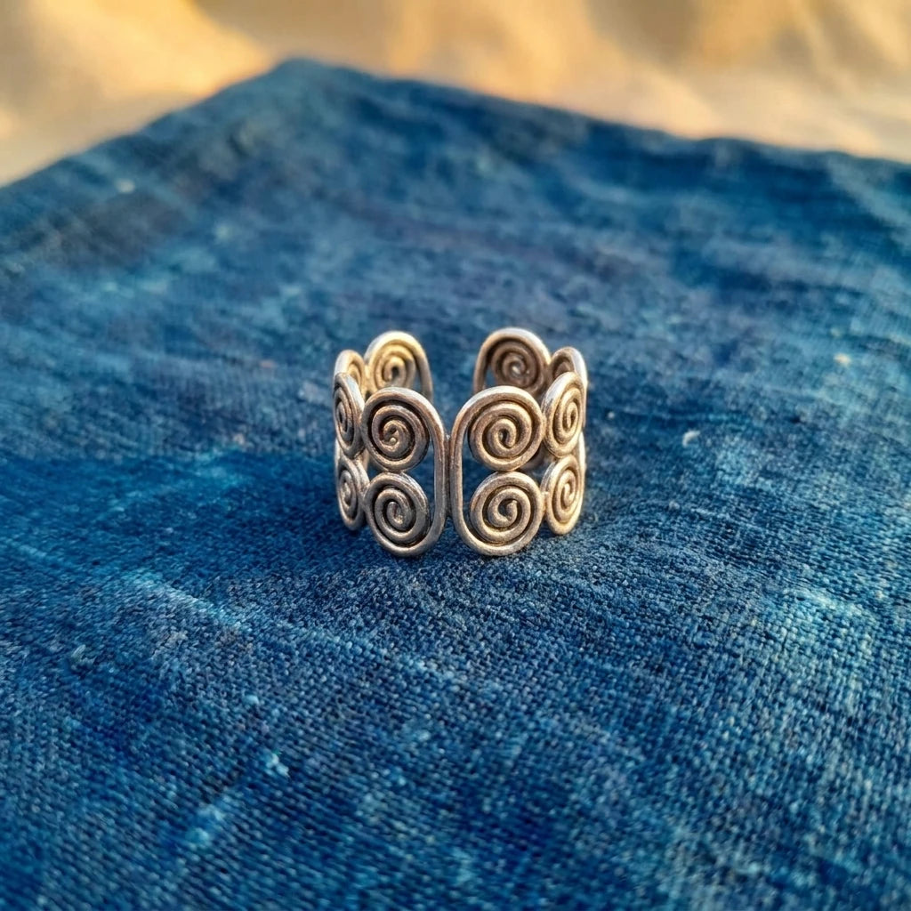 Miao Silver Double Spiral Adjustable Ring displayed on indigo textile